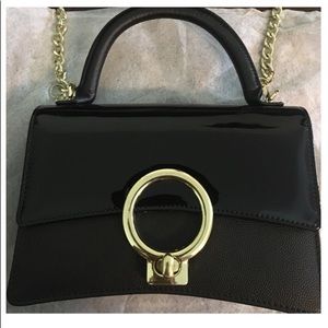 Black patent leather and caviar leather satchel with gold turn lock and chain.
